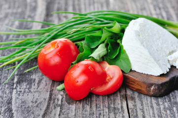 Tomatoes with onion and cheese on a wooden board