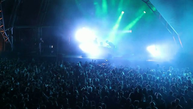 Huge crowd dancing at a DJ show, with great lightning effects
