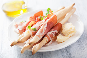 prosciutto ham and grissini bread sticks. italian antipasto