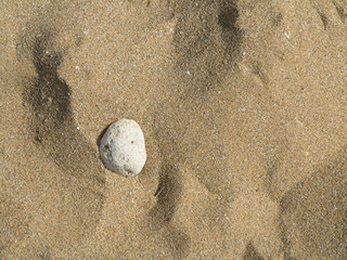 Single round white stone on a sandy beach