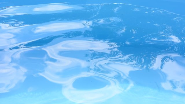 Blue water surface with waves in the swimming pool.