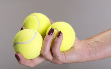 Three tennis balls in a players hand