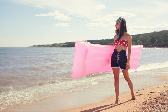 Stylish pinup girl posing with swimming mattress