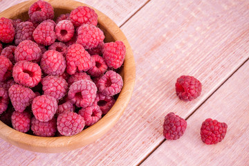 fresh ripe raspberries in a bowl on a wooden background