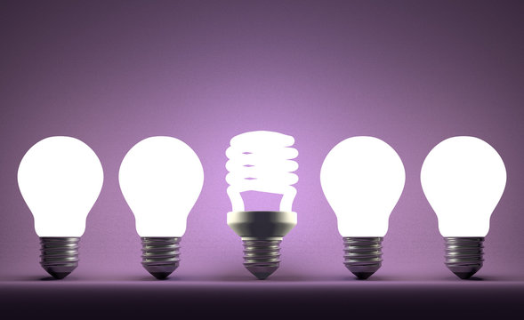 Glowing spiral light bulb in row of tungsten ones on violet
