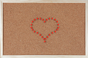Heart made of pushpins on corkboard