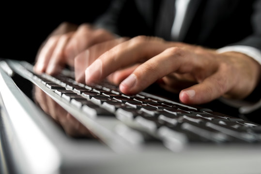 Hands of a man typing fast on a computer keyboard