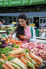 Pretty young woman buying vegetables on the market