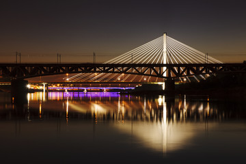 Fototapeta na wymiar Backlit bridge at night and reflected in the water