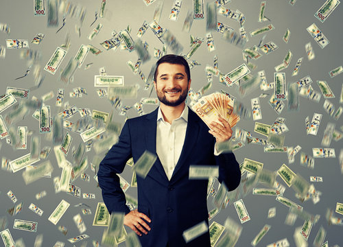 happy businessman standing under money rain