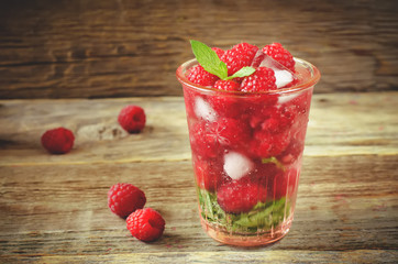 Summer juice with fresh raspberries mint and ice in a glass