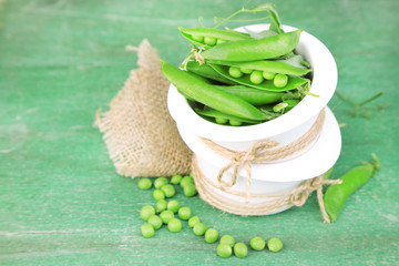 Fresh green peas in bowl on wooden table
