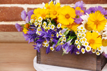 Beautiful flowers in crate on brick wall background