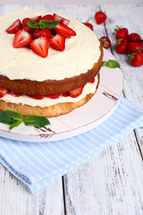 Delicious biscuit cake with strawberries on table close-up