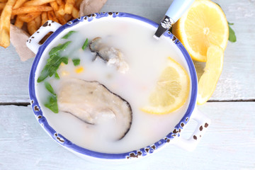 Tasty soup with oysters on wooden table