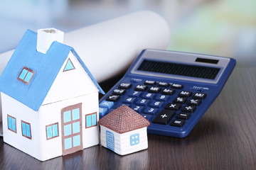 Toy houses and calculator on table close-up