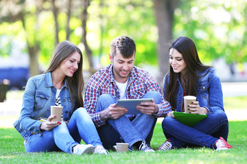 Happy students sitting in park