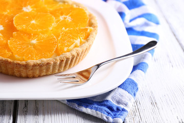 Homemade orange tart on plate, on color wooden background