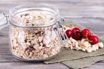 Homemade granola in glass jar, on color wooden background