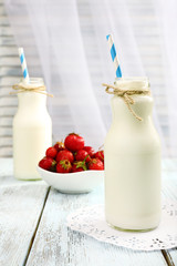 Milk in bottles with paper straws on table