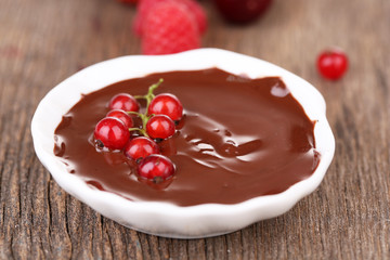 Ripe sweet berries and liquid chocolate on wooden table