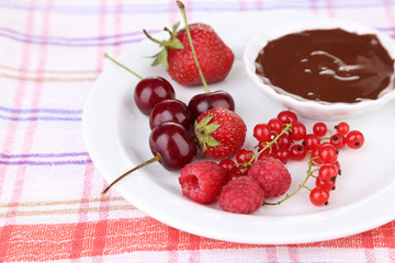 Ripe sweet berries and liquid chocolate on tablecloth