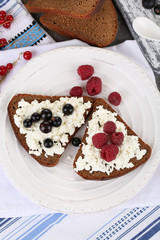 Bread with cottage cheese and berries on plate close-up