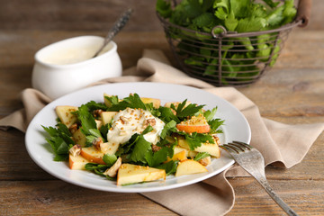 Green salad with apples, walnuts and cheese on wooden