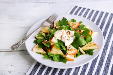 Green salad with apples, walnuts and cheese on wooden