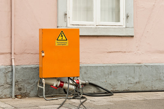 Ein oranger Baustromverteiler und angeschlossene Starkstromkabel