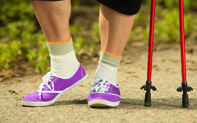 Fototapeta na wymiar mature woman legs nordic walking in park