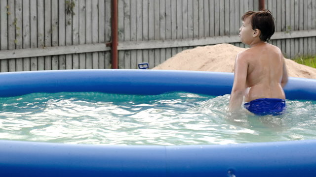 Boy swimming in inflatable pool in the yard