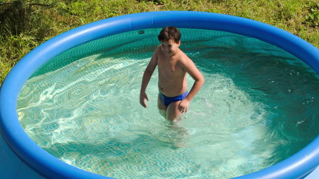 Boy having fun in outdoor pool on a hot summer day