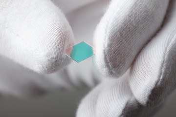 Hand in glove hold small piece of thin glass, new material