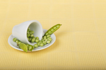 Fresh green peas in an inverted white cup