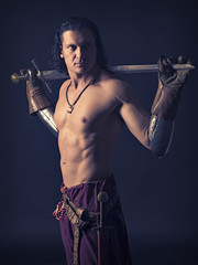half-naked man with a sword in medieval clothes on a dark backgr