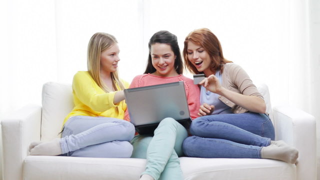 smiling teenage girls with laptop and credit card
