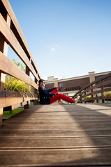 Stylish man sitting on wooden bridge.
