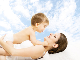 Mother baby happy playing. Child in diaper embracing mama sky