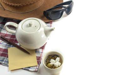cup of tea with teapot, hat, sunglasses, paper, pen and cloth