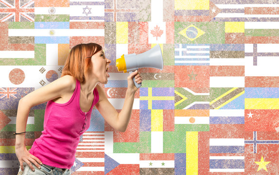 Redhead girl shouting with a megaphone over flags background