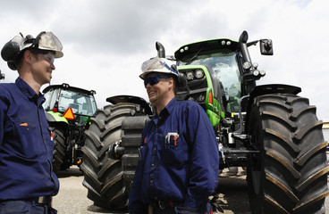 two mechanics standing in front of giant farming tractors