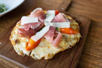 Pizza with parma ham on wooden tray.