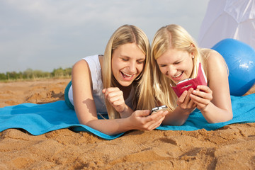 Zwei junge Frauen am Strand mit Smartphone