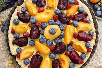 Sweet tart with peaches, plums and blueberries - obrazy, fototapety, plakaty