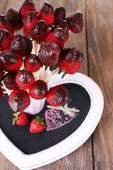 Strawberry in chocolate on skewers in cup on table close-up