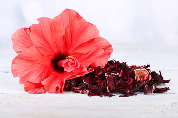 Hibiscus tea and flower on wooden table, on light background