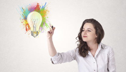 Young lady drawing a colorful light bulb with colorful splashes