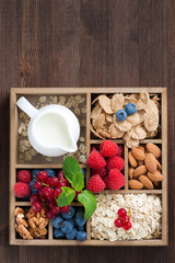wooden box with breakfast items - oatmeal, granola, nuts, berry