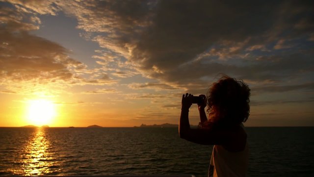 Woman Taking a Photo of Sunset from the Sailing Boat. Slow